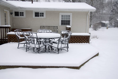 A backyard deck covered in snow during a blizzard