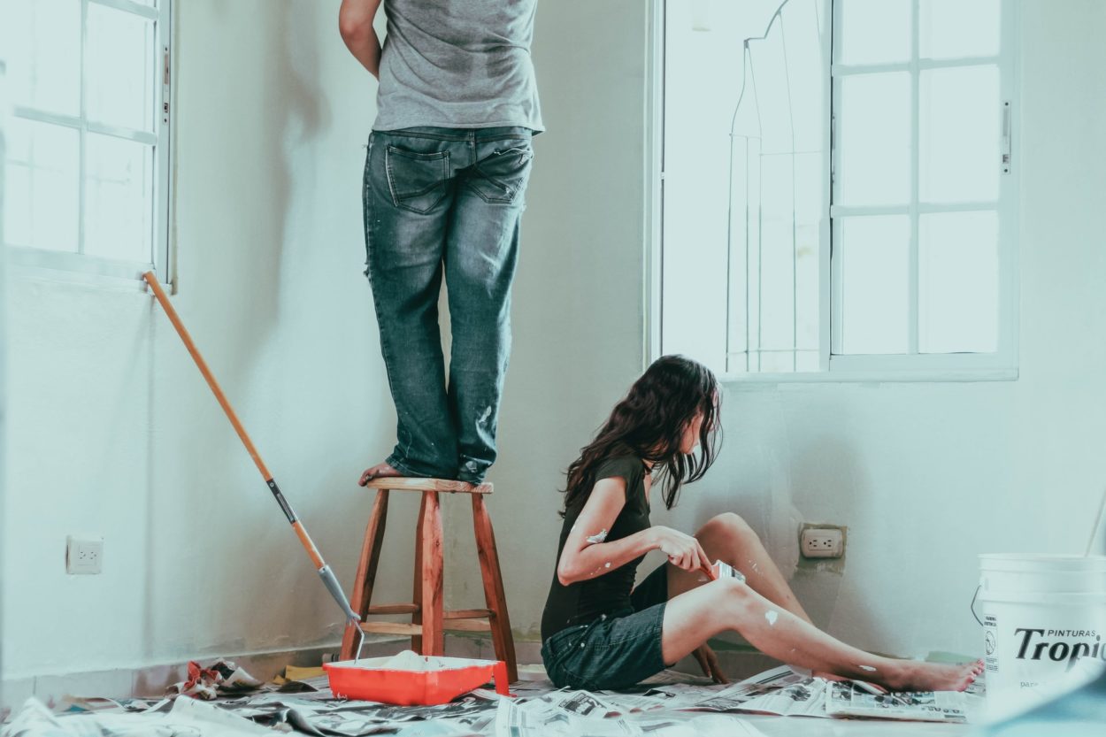 A man and woman pain the corner of a room as a home improvement project.