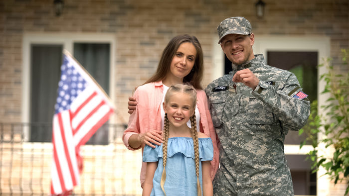 A military family stands in front of their new home after a relocation.